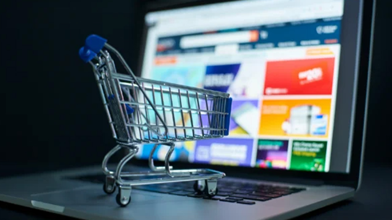 A mini shopping cart sitting on a laptop computer